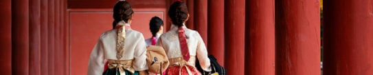 Asian girls in hanbok dress walking between the red pillar of Autumn Leaves Park