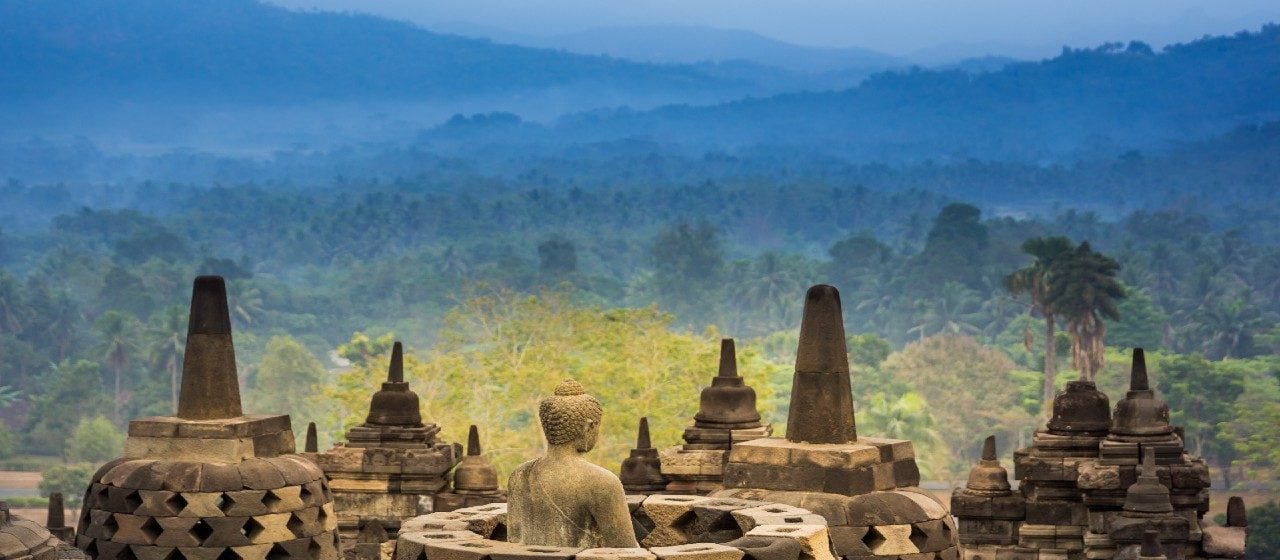 Openwork stupas of Borobudur Temple against a backdrop of lush jungle