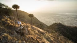 Travellers on rock edge looking out over a deep valley in Mwiba Wildlife Reserve, Tanzania