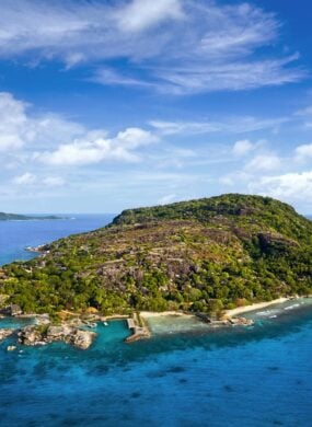 A small island with white beaches, coral reefs, and forests