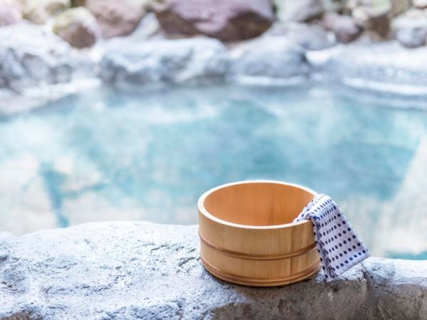 Japanese hot spring, open-air bath with wooden pot and blue and white spotted towel on the edge