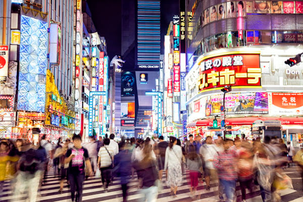 Crowd of People Crossing big zebra crossing at night, lit by neon signs in Tokyo, Japan