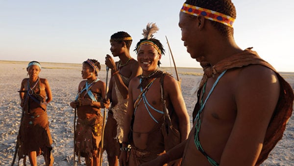 People dressed in traditional African tribal clothing standing in a dry plain