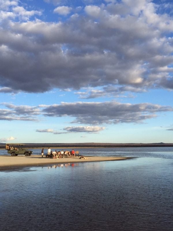 Group of travellers gathered around an unlit campfire on the edge of Lake Manyara, Tanzania