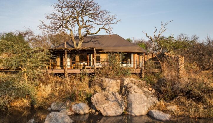 External shot of suite at Mwiba Lodge, a building with outdoor seating area in front of a river