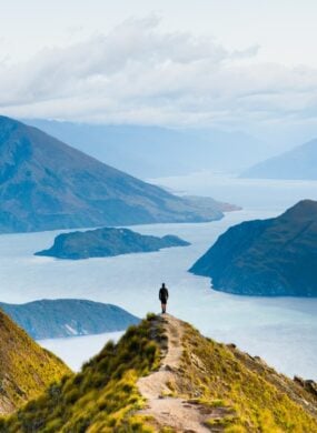 Hiker on Roys Peak overlooking Lake Wanaka and the surrounding mountains