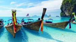 Long tail boats lined up along in shallow water in a bay in Thailand