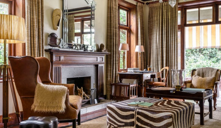 Interior of Singita Sasakwa living area, armchairs and coffee table facing open fireplace, Singita Grumeti Tanzania